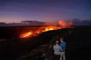 man and woman watching volcano erupt