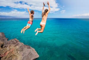 man and woman jumping off cliff into the ocean, cliff jumping