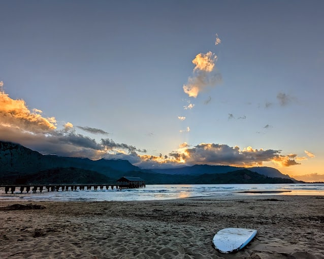 A long pier leading into the ocean with clouds in sky