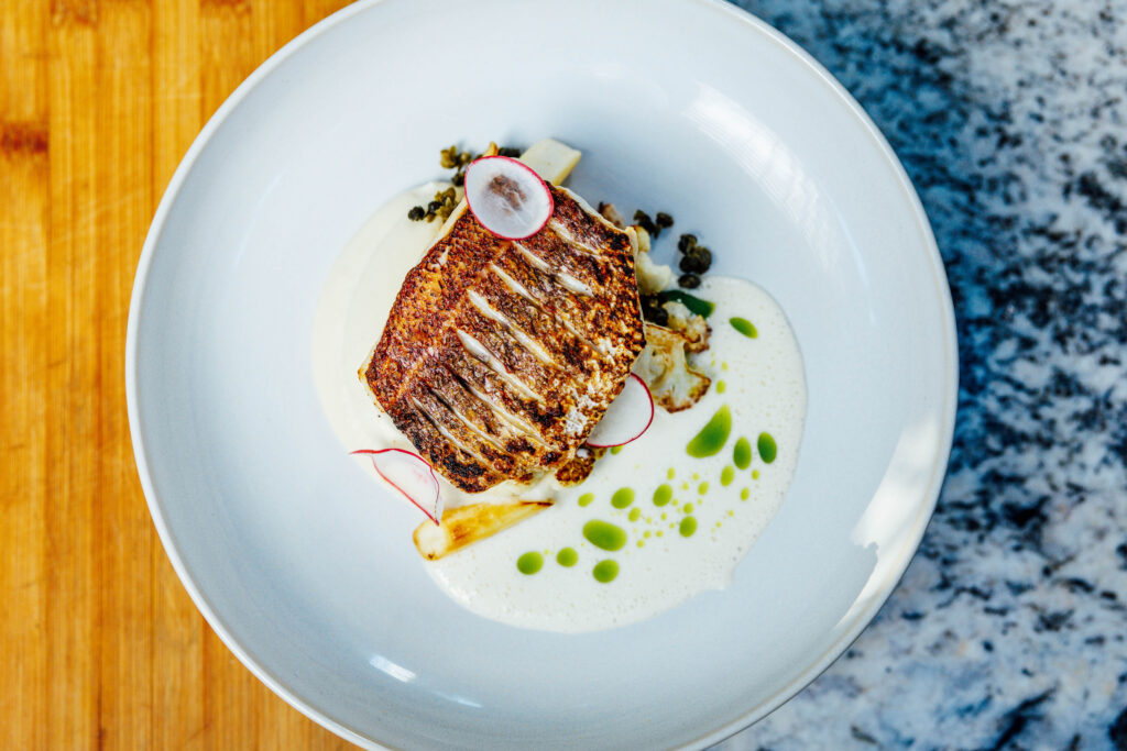 Seared Kanpachi with cauliflower puree, market vegetables and yuzu-kosho dashi emulsion at Aurum. Photo by Sebastian Sayegh/Sayegh Visuals
