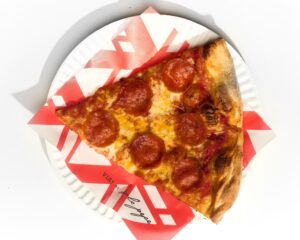 Pepperoni pizza slice on red and white paper on paper plate from Via! by Sale Pepe in Lahaina, Maui, Hawaii.